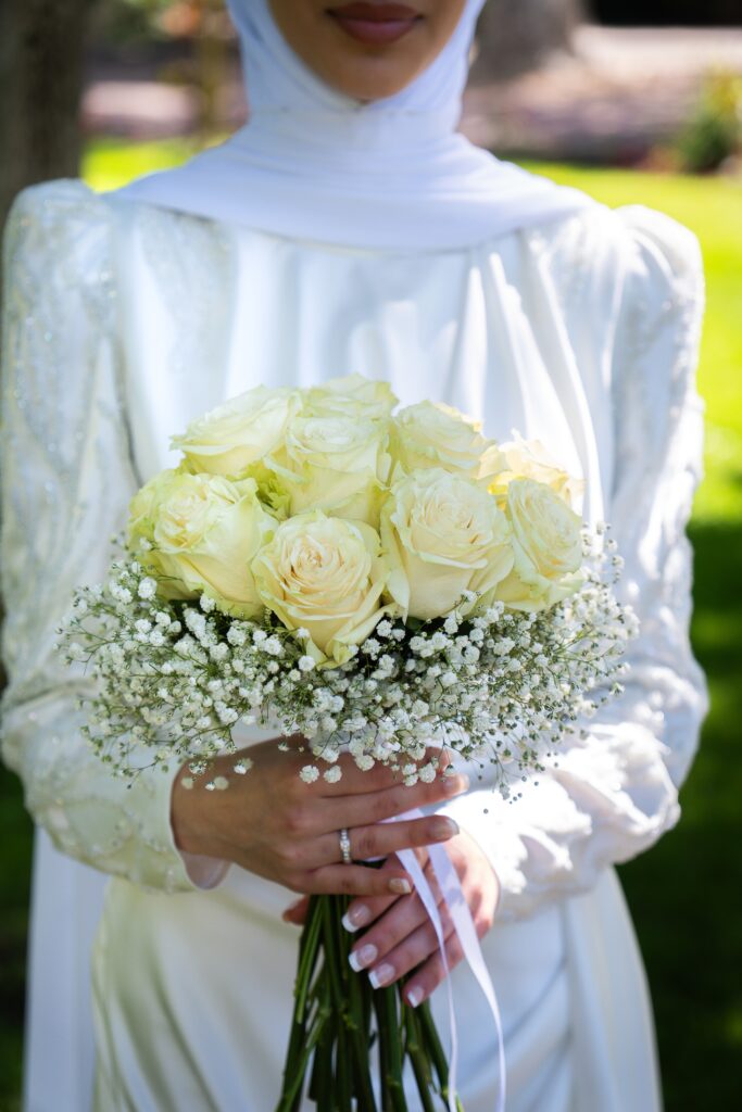 Photo de mariage montrant le bouquet de la mariée tenu dans ses mains, sans montrer son visage. Un détail élégant capturant la beauté et l’émotion de l’instant.